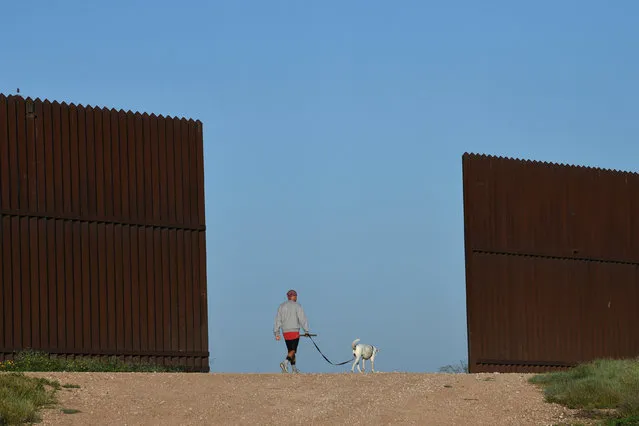 A man walks his dog past a stretch of border fence in the Rio Grande Valley near Penitas, Texas, U.S., April 8, 2019. (Photo by Loren Elliott/Reuters)