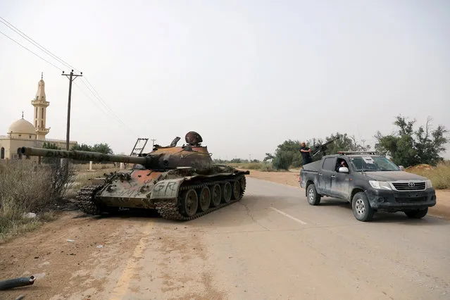 Members of Libyan internationally recognised government forces pass near a damaged tank belonging to Eastern forces in Al Hira area, south western Tripoli, Libya on April 23, 2019. (Photo by Hani Amara/Reuters)