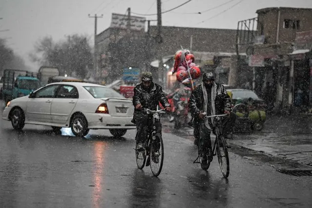 Men ride bicycles along a road during the first snow in Kabul on December 15, 2021. (Photo by Mohd Rasfan/AFP Photo)