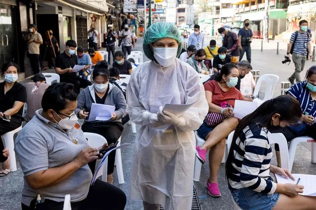 A medical worker assists people with registration, as hospitality and tourism workers are tested for the Covid-19 coronavirus on Khao San Road, in Bangkok on January 6, 2022. (Photo by Jack Taylor/AFP Photo)