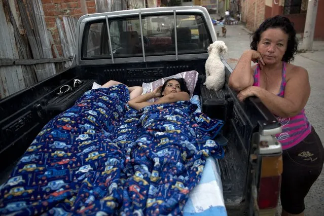 Two women begin to stir from their sleep in the bed of a pickup, parked outside their earthquake-damaged home in Manta, Ecuador, Wednesday, April 20, 2016. A fresh tremor rattled Ecuador before dawn Wednesday, a magnitude-6.1 magnitude jolt that set babies crying and adults pouring into the streets, fearful of yet more damage following the 7.8-magnitude earthquake over the weekend. It was the strongest aftershock yet following Saturday's monster quake that killed more than 500 people. (Photo by Rodrigo Abd/AP Photo)