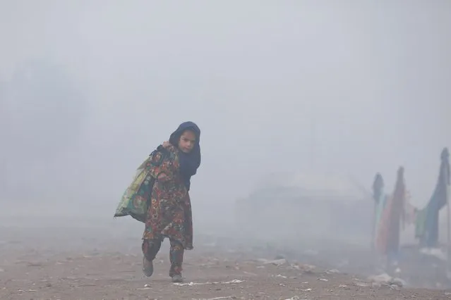 A girl carries a sack of recyclables as she walks amid fog during morning hours in Peshawar, Pakistan, January 10, 2022. (Photo by Fayaz Aziz/Reuters)