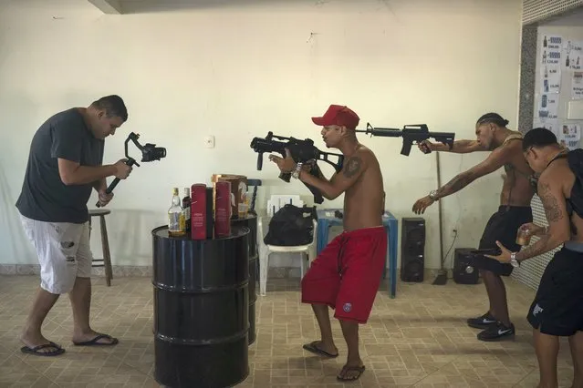 Trap de Cria artists Marcos Borges, known as “MbNaVoz”, center, Pablo “PBSant”, second right, and Fernando “Barbeirin”, right, hold Airsoft guns as cameraman Clayton Oliver, left, records a music video for the song “Se Tem Glock” in the Jardim Catarina community in Sao Gonçalo, Rio de Janeiro state, Brazil, Sunday, April 11, 2021. Trap de Cria has a lyrical flow over synthesized drums, and is comparable to U.S. gangsta rap in speaking to the day-to-day struggles of hardscrabble hoods while depicting gang life. (Photo by Felipe Dana/AP Photo)