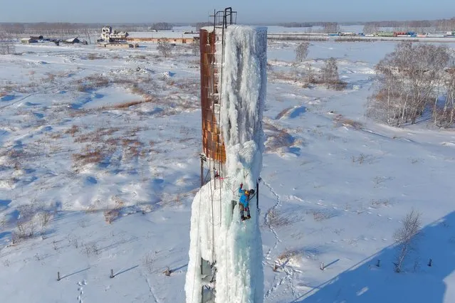 A man climbs a water tower as part of an ice climbing training session held by the Spektr recreation club in Novosibirsk Region, Russia on January 30, 2022. (Photo by Kirill Kukhmar/TASS)