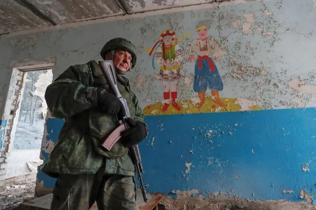 A militant of the self-proclaimed Luhansk People's Republic patrols the damaged building of a local school located near the line of separation from the Ukrainian armed forces in the settlement of Molodizhne (Molodezhnoye) in the Luhansk region, Ukraine on February 17, 2022. (Photo by Alexander Ermochenko/Reuters)