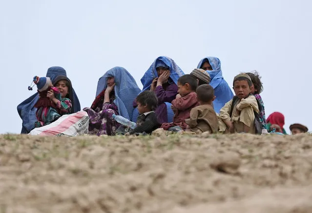 In this Sunday, May 4, 2014 photo, Survivors sit with their possessions near the site of Friday's landslide that buried Abi-Barik village in Badakhshan province, northeastern Afghanistan. Stranded and with no homes, many of the families have struggled to get aid. Some have gone to nearby villages to stay with relatives or friends, while others have slept in tents provided by aid groups. (Photo by Massoud Hossaini/AP Photo)