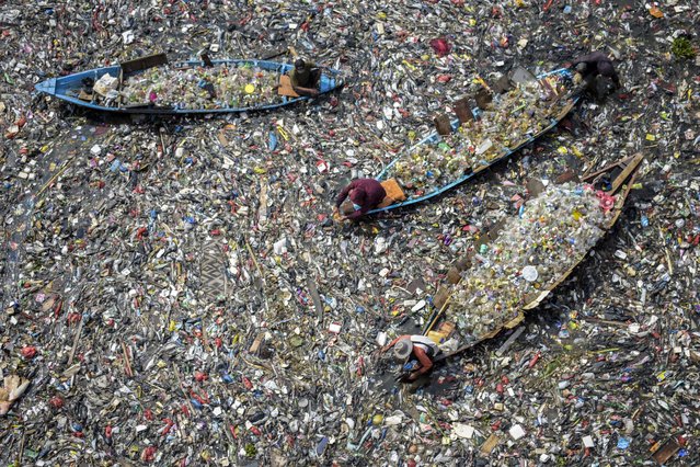 People on boats collect recyclable plastics from the heavily polluted Citarum River at Batujajar in Bandung, West Java, on June 12, 2024. (Photo by Timur Matahari/AFP Photo)