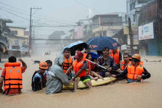 Rescuers assist residents on a boat as they wade through a flooded road following heavy rains brought by Typhoon Gaemi, in Marikina City, Metro Manila, Philippines, on July 24, 2024. (Photo by Lisa Marie David/Reuters)