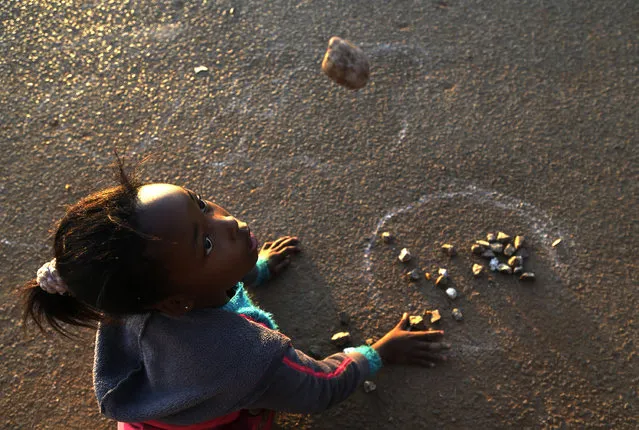 In this Wednesday, July 8, 2015 photo, Ellen Rathobotha, plays a indigenous game called “Diketo” in in Kagiso, west of Johannesburg, South Africa. In the game, which requires good hand-eye coordination, stones are placed in a circle or a square and each player then tries to grab the most stones, throw them in the air and catch them in one hand until all the stones are back in the circle or square. (Photo by Themba Hadebe/AP Photo)