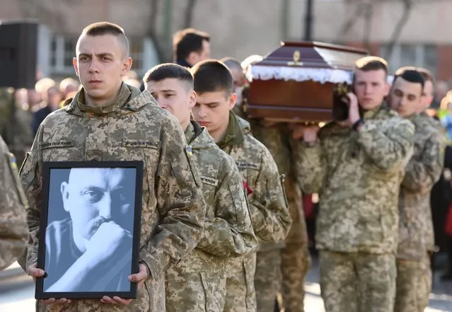 Brothers in arms of serviceman of Right Sector, Ukrainian Volunteer Corps, Taras Bobanych, call sign Hammer, who died during the conflict with Russia, carry his portrait and coffin during his funeral ceremony at the Lychakiv Cemetery in the western Ukrainian city of Lviv on April 13, 2022, amid Russia's invasion launched on Ukraine. (Photo by Yuriy Dyachyshyn/AFP Photo)