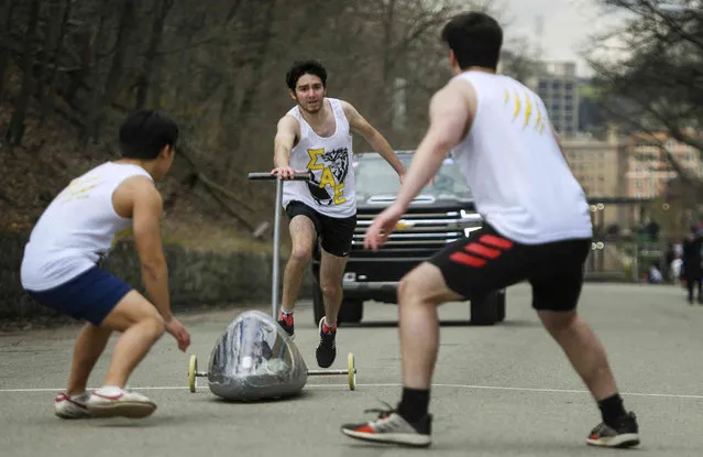 James Kramer, center, pushes the SAE team's handmade non-motorized, carbon fiber racing vehicle to the finish line, where teammates rush to stop it, during Carnegie Mellon University's annual Buggy Sweepstakes in Pittsburgh on Friday, April 8, 2022. Kramer is a freshman at CMU. Students have competed in the annual race since 1920. Teams of five runners use the buggy as a baton, passing it along in a sort of relay race around a course that's nearly one mile long. The buggies are steered by student drivers who squeeze into the vehicles. (Photo by Steve Mellon/Pittsburgh Post-Gazette via AP Photo)