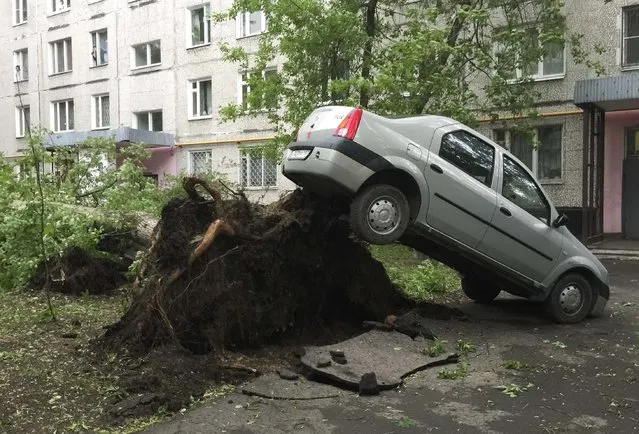 A view shows a car lifted by the roots of a tree, which was toppled during a heavy storm, in Moscow, Russia, May 29, 2017. (Photo by Alexander Panchenko/Reuters)