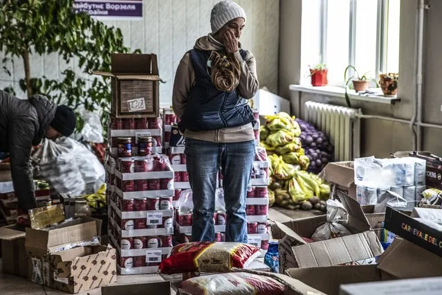 Larissa Shudeva, a resident  of Vorzel  at a school with her pet dog as she pauses during her volunteer dealing with food and clothing donations collected for those in need in Vorzel,Ukraine a suburb of Kyiv on April 13, 2022. (Photo by Heidi Levine/The Washington Post).