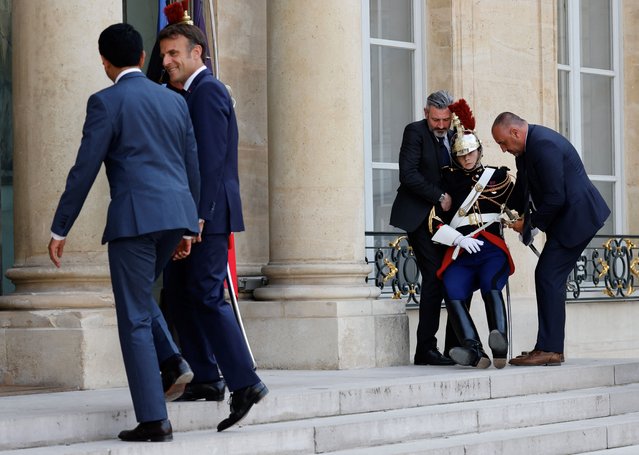 France's President Emmanuel Macron (2ndL) welcomes Madagascar's President Andry Rajoelina (L) as a Republican gard (R) who has fainted due to the heat is helped by officials, at the Elysee Palace in Paris, on June 9, 2023. (Photo by Ludovic Marin/AFP Photo)