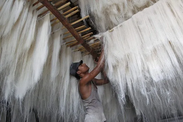 A worker hangs strands of vermicelli, a specialty eaten during the Muslim holy fasting month of Ramadan, to dry at a factory in Allahabad, India, June 7, 2016. (Photo by Jitendra Prakash/Reuters)