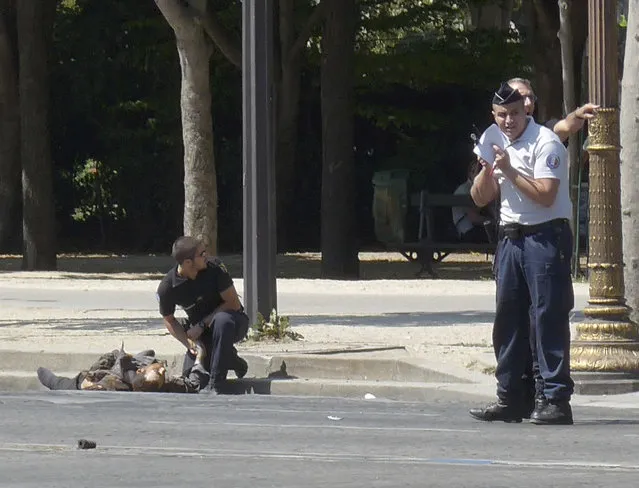 In this photo provided by Noemie Pfister, a French gendarme kneels near the dead body of a man who rammed into a police convoy and detonated an explosive device on the Champs Elysees avenue in Paris, France, Monday, June 19, 2017. Two French police officials say the man who rammed into a police convoy on Paris' Champs-Elysees was a 31-year-old man from a Paris suburb who had been flagged for extremism. (Photo by Noemie Pfister via AP Photo)