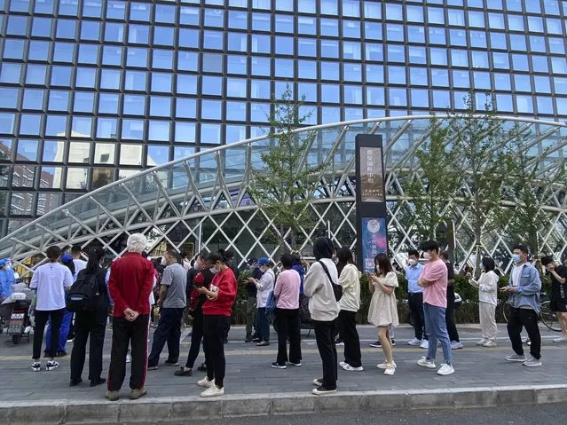 People wearing face masks stand in line for COVID-19 tests at a testing site during the second consecutive day of mass testing in Beijing, Wednesday, May 4, 2022. Beijing on Wednesday closed around 10% of the stations in its vast subway system as an additional measure against the spread of coronavirus. (Photo by Mark Schiefelbein/AP Photo)