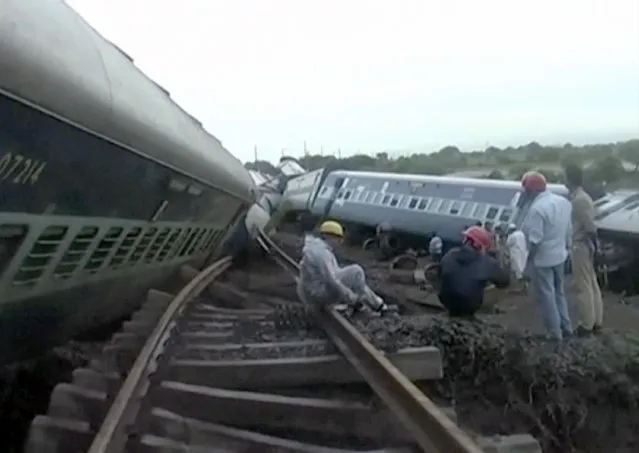 In this image made from video, people gather by the twisted track alongside two derailed trains in Harda in Madhya Pradesh state, India, Wednesday, August 5, 2015. (Photo via AP Video)