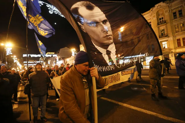 Activists of various nationalist parties carry torches and a portrait of Stepan Bandera during a rally in Kyiv, Ukraine, Wednesday, January 1, 2020. The rally was organized to mark the birth anniversary of Stepan Bandera, founder of a rebel army that fought against the Soviet regime and who was assassinated in Germany in 1959. (Photo by Efrem Lukatsky/AP Photo)