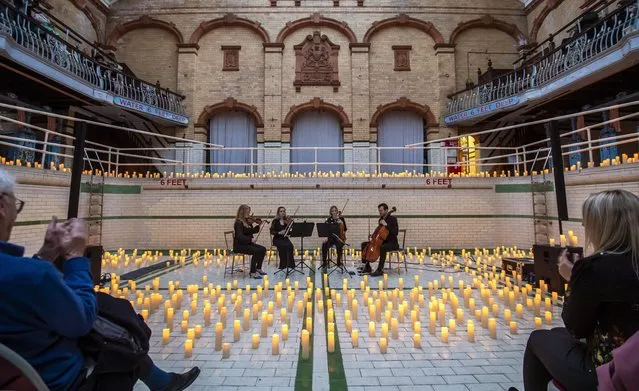 The Bloomsbury String Quartet perform in the empty swimming pool during the Vivaldi And Mozart Candlelit Concert At Victoria Baths on May 26, 2022 in Manchester, England. Opened in 1906, Victoria Baths was described as “the most splendid municipal bathing institution in the country” and “a water palace of which every citizen of Manchester can be proud”.  Not only did the building provide spacious and extensive facilities for swimming, bathing and leisure, it was built of the highest quality materials with many period decorative features including stained glass, terracotta, tiles and mosaic floors. (Photo by Anthony Devlin/Getty Images)