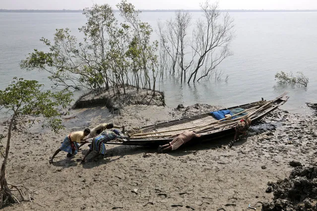 In this February 1, 2015 file photo, villagers help a fisherman couple push their boat to the water at Satyanarayanpur village in the Sundarbans, India, an area straddling India and Bangladesh where thousands are homeless as seas rise twice as fast as the global average and water eats away at the islands or subsumes them altogether. A report by the Asia Development Bank on Friday, July 14, 2017, says Asia will endure extreme heat, rising sea levels, growing losses from severe weather and increasing food insecurity in coming decades as climate change raises temperatures and alters weather patterns across the globe. (Photo by Bikas Das/AP Photo)