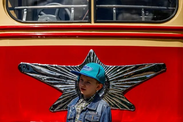 A boy stands near a retro tram during a parade of retro transport in the centre of Moscow, Russia on June 4, 2022. (Photo by Maxim Shemetov/Reuters)