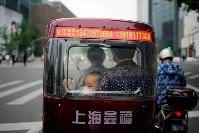 A child wearing a face mask sits inside a tricycle on a road, after the lockdown placed to curb the coronavirus disease (COVID-19) outbreak was lifted in Shanghai, China on June 1, 2022. (Photo by Aly Song/Reuters)