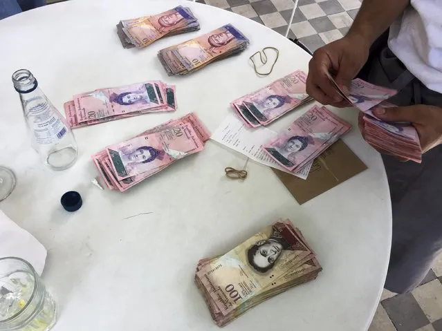 A waiter counts Venezuelan bolivar notes, corresponding to the bill for a lunch of 4 people, at a restaurant in Caracas July 14, 2015. The bill was 13,126 bolivars, equivalent to 2,067 U.S. dollars at the official exchange rate of 6.3 bolivars per dollar or approximately 20 U.S. dollars according to the black market exchange rate. (Photo by Carlos Garcia Rawlins/Reuters)