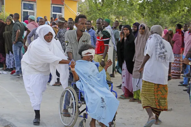 A civilian who was wounded in suicide car bomb attack is helped to be taken to hospital in Mogadishu, Somalia, Saturday, December 28, 2019. A police officer says a car bomb has detonated at a security checkpoint during the morning rush hour in Somalia's capital. (Photo by Farah Abdi Warsame/AP Photo)