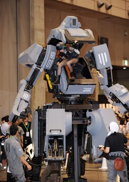 Female “pilot” Anna (C) climbs out the cockpit of Japanese electronics company Suidobashi Heavy Industry's newly unveiled robot “Kuratas” at the Wonder Festival in Chiba, suburban Tokyo on July 29, 2012. The Kuratas robot, which will go on sale with a price tag of one million USD, measures four meters in height, weighs four tons and has four wheeled legs that can either be controlled remotely through the 3G network or by a human seated within the cockpit.