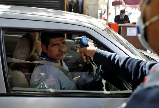 A man arriving into an office building gets his temperature measured by a private security guard using an infrared thermometer, following an outbreak of the coronavirus disease, in New Delhi, India, March 9, 2020. (Photo by Adnan Abidi/Reuters)