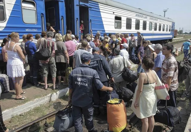 Refugees from the Luhansk region wait to board a train terminating in Kharkiv, at a railway station near the town of Svatovo August 12, 2014. (Photo by Stanislav Belousov/Reuters)