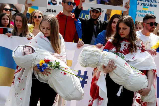 Women carry dummy babies, symbolizing children who were killed in the conflict, as they take part in a demonstration in support of Ukraine, amid Russia's invasion of the country, in Budapest, Hungary, April 30, 2022. (Photo by Bernadett Szabo/Reuters)