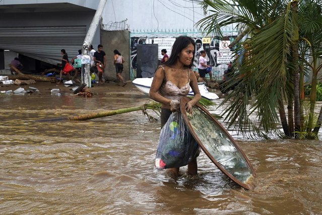 A woman walks away with stuff she looted from a furniture store after Hurricane Otis ripped through Acapulco, Mexico, Wednesday, October 25, 2023. Hurricane Otis ripped through Mexico's southern Pacific coast as a powerful Category 5 storm, unleashing massive flooding, ravaging roads and leaving large swaths of the southwestern state of Guerrero without power or cellphone service. (Photo by Marco Ugarte/AP Photo)
