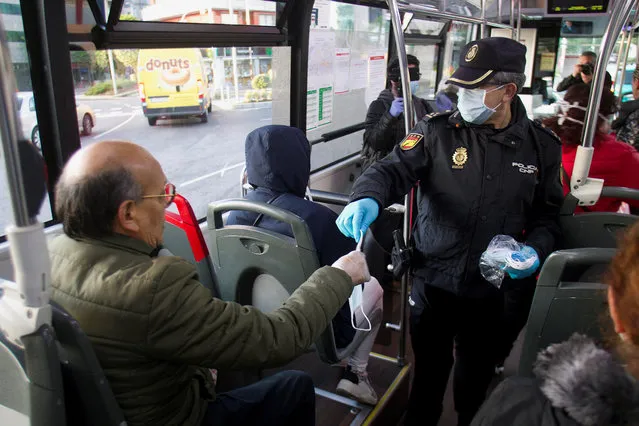A commuter receives a mask from a policeman on board a bus in Vigo, northwestern Spain, 13 April 2020. Central government decided that some non-essential economic activities will resume its work from 13 April after two weeks amid the lockdown caused by coronavirus outbreak. Authorities will deliver some 10 million mask until next 15 April. (Photo by Salvador Sas/Reuters)