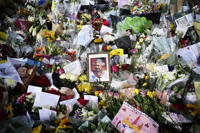 A picture of Britain's Queen Elizabeth II is seen amongst flowers put down by well-wishers outside of Buckingham Palace in London on September 10, 2022, two days after she died at the age of 96. -ing Charles III pledged to follow his mother's example of “lifelong service” in his inaugural address to Britain and the Commonwealth, after ascending to the throne following the death of Queen Elizabeth II on September 8. (Photo by Loic Venance/AFP Photo)