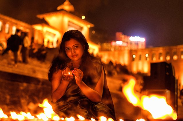 A lady poses for a photo while holding a Diya (Soil Made Lamp) during the Dev Deepavali Festival at Varanasi, India on November 25, 2023. Dev Deepavali / Diwali is the biggest festival of light celebration in Kartik Poornima (Mid-Autumn) where devotees decorate the river bank with millions of lamps during the festival. (Photo by Avishek Das/SOPA Images/Rex Features/Shutterstock)