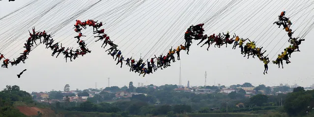 People jump off a bridge, which has a height of 30 meters, in Hortolandia, Brazil, October 22, 2017. According to organisers, 245 people were attempting set a new world record for “rope jumping”, in which people, tied to a safety cord, jump off a bridge. (Photo by Paulo Whitaker/Reuters)