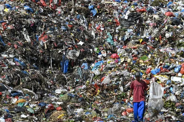 A scavenger goes through a pile of waste at a dump site in Banda Aceh on September 15, 2022. (Photo by Chaideer Mahyuddin/AFP Photo)