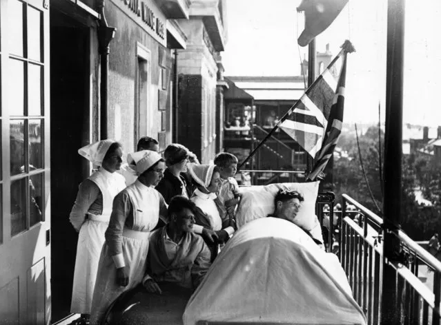 Fusilier Grinsey (in bath chair) and Lance Corporal (in bed) watch the march past of their regiment (the 2nd City of London Royal Fusiliers) from the balcony of the Royal Sussex County Hospital. Matron is holding up the Lance Corporal's son. 13th August 1933. (Photo by H. F. Davis/Topical Press Agency)