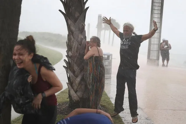 People take shelter behind trees from the high winds and rain as Hurricane Irma approaches on September 9, 2017 in Miami Beach, Florida. Florida is in the path of the Hurricane which may come ashore at category 4. (Photo by Joe Raedle/Getty Images)
