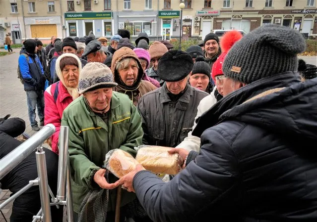 Local residents stand in line waiting for free bread from volunteers in Bakhmut, the site of the heaviest battle against the Russian troops in the Donetsk region, Ukraine, Friday, October 28, 2022. (Photo by Efrem Lukatsky/AP Photo)