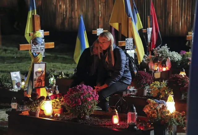 Ukrainians light candles as they visit the graves of Ukrainian soldiers killed in the war with Russia at the Lychakiv Cemetery in Lviv, Western Ukraine, 01 November 2022, as they mark the All Saints' Day and Day of the Dead. Russian troops on 24 February entered Ukrainian territory, starting a conflict that has provoked destruction and a humanitarian crisis. (Photo by Mykola Tys/EPA/EFE)