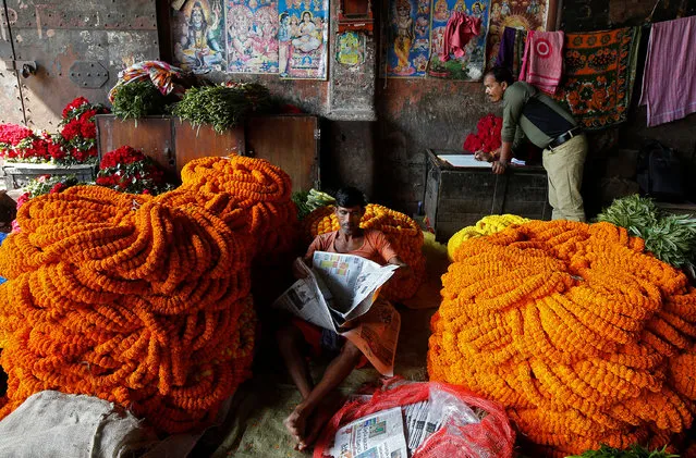 A man reads a newspaper next to marigold garlands, which are used to decorate temples and homes, at a wholesale flower market in Kolkata, India, November 21, 2017. (Photo by Rupak De Chowdhuri/Reuters)