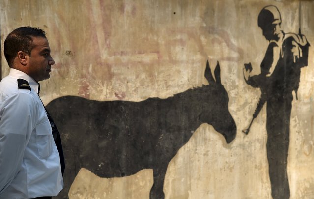 A private security officer stands on duty near an art piece by British artist Banksy entitled “Donkey Documents”,  at the Design Centre in Chelsea, west London, September 21, 2015. Banksy created the piece in 2007 as part of a series of works of art along the concrete barrier separating the Palestinian West Bank and Israel. It is the largest, most significant intact mural from the artist's visit to Israel, and will be auctioned in the U.S. next month with a predicted sale price of approximately $600,000. (Photo by Toby Melville/Reuters)