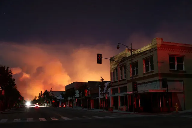 Downtown is darkened by a power outage with smoke rising in the distance as strong winds push the Thomas Fire across thousands of acres in Santa Paula, Calif., December 5, 2017. (Photo by David McNew/Reuters)