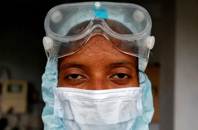 Beads of sweat run down the forehead of a healthcare worker wearing protective gear after she took swabs for a rapid antigen test from residents at a residential apartment in Ahmedabad, India, July 23, 2020. (Photo by Amit Dave/Reuters)