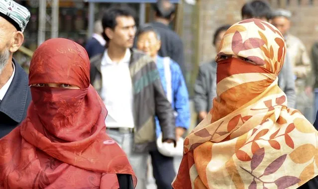 Uighur women wearing face veils walk on a street in Urumqi September 17, 2013. The custom of women wearing face veils is not a tradition of minority people in China's western area of Xinjiang or in any Muslim country, but is a symbol of extremism and backwardness instead, a senior regional official said on September 24, 2015. (Photo by Reuters/Stringer)