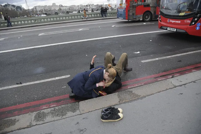 A woman assists an injured person after an incident on Westminster Bridge in London, March 22, 2017. (Photo by Toby Melville/Reuters)