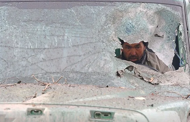 An Afghan truck driver is seen through the broken windshield of his vehicle at the site of a suicide attack near the Afghan intelligence agency headquarters in Kabul. A squad of suicide bombers attacked the national intelligence agency headquarters in heavily-fortified central Kabul on January 16, killing at least two guards and wounding dozens of civilians, officials said. (Photo by Shah Marai)